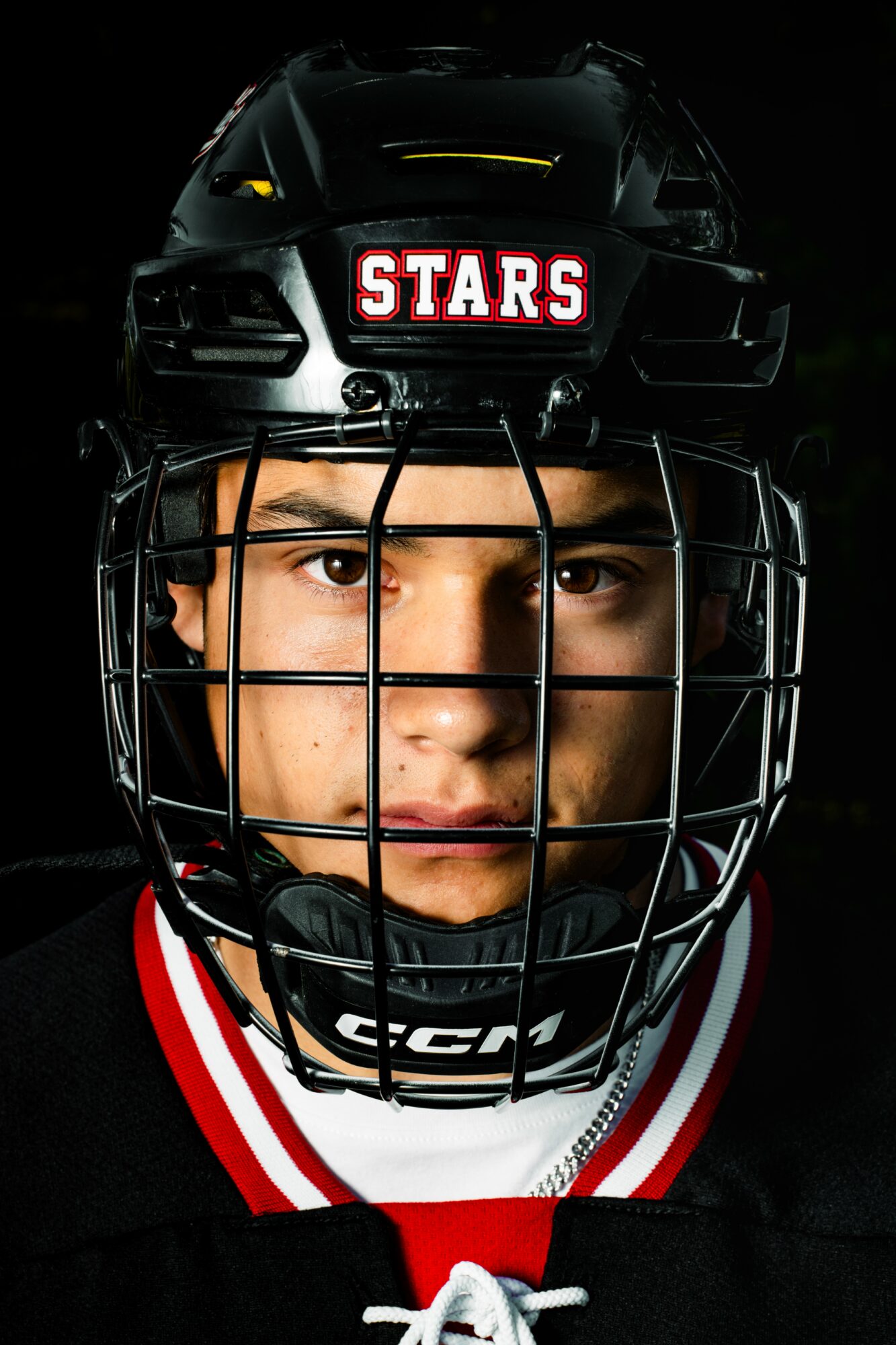 Close-up of a young person wearing a hockey helmet with a cage, looking directly at the camera.