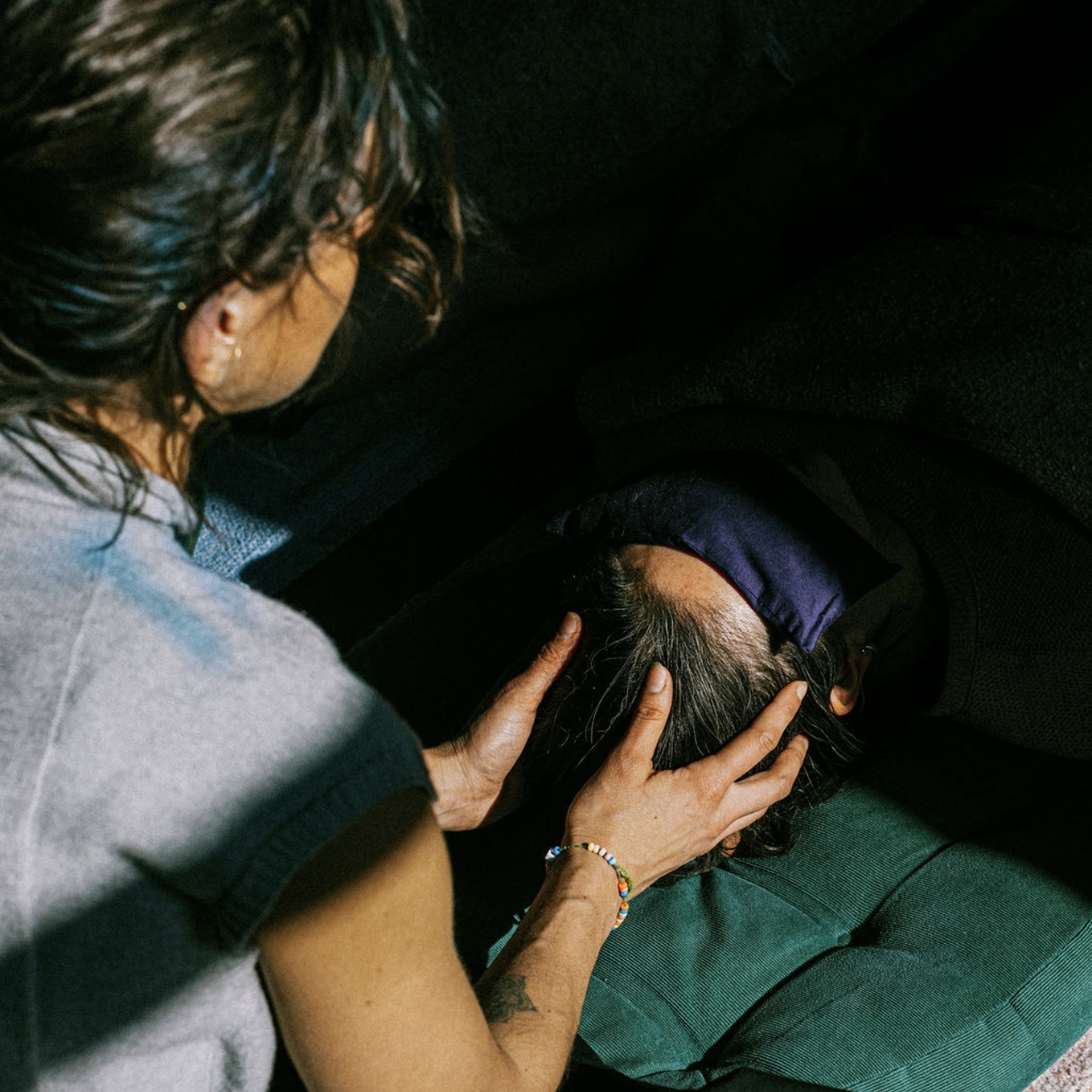 Person holding a child's head in a dark setting, with the child's face not visible.