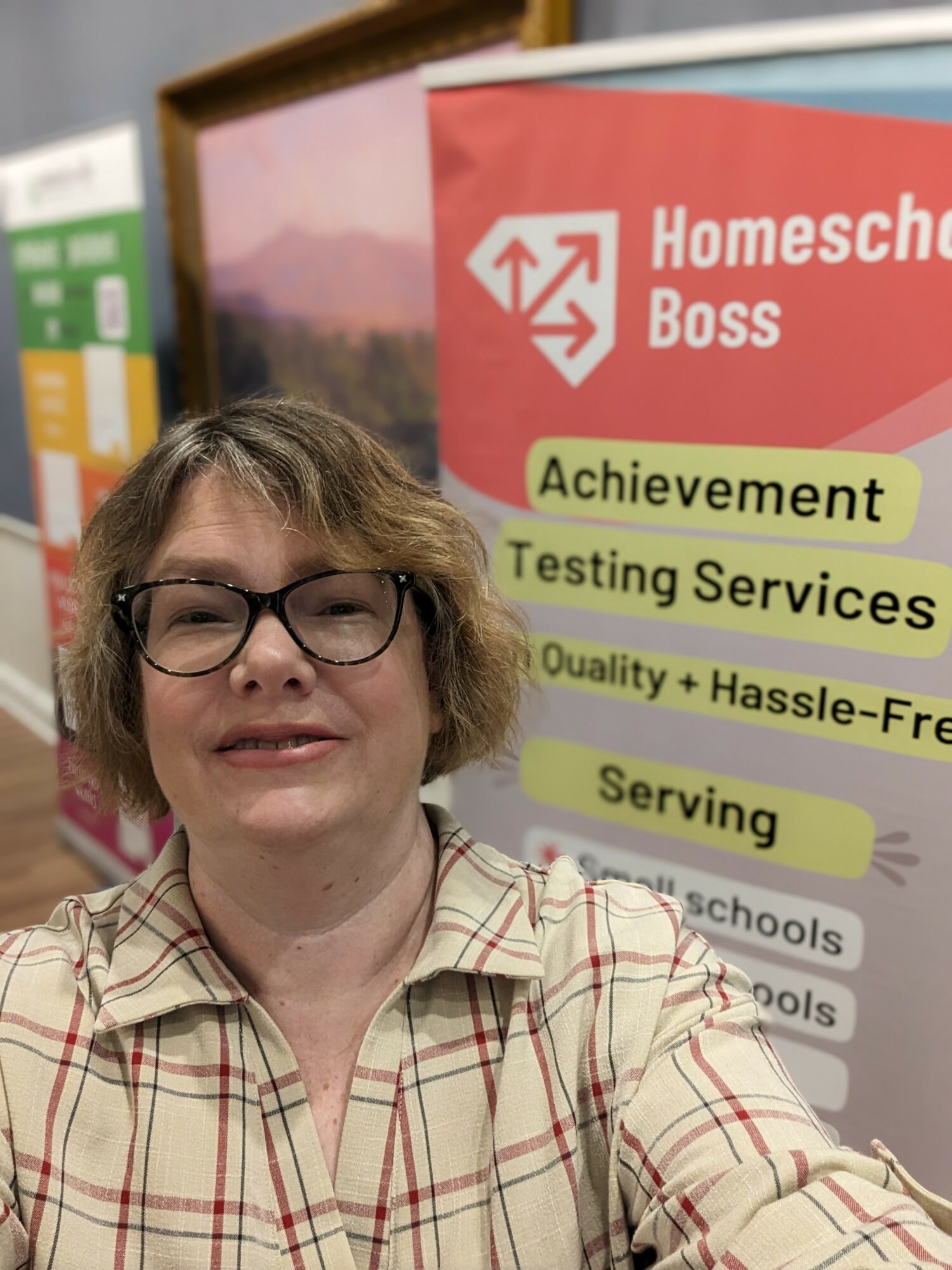 Woman with glasses smiling in front of a pink and green Homeschool Boss banner.