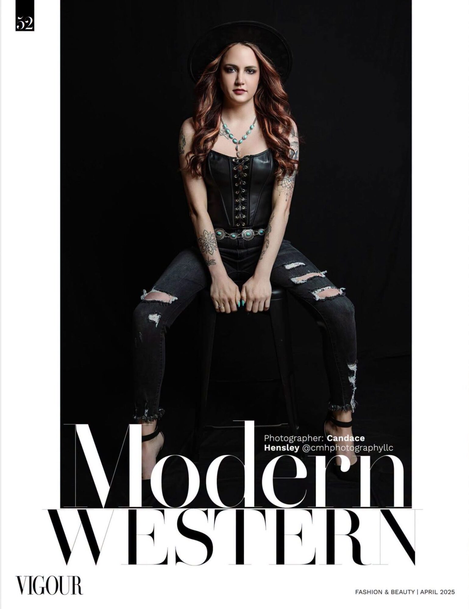 Young woman with long hair wearing a black hat, black top, ripped jeans, and jewelry, sitting against a dark background.