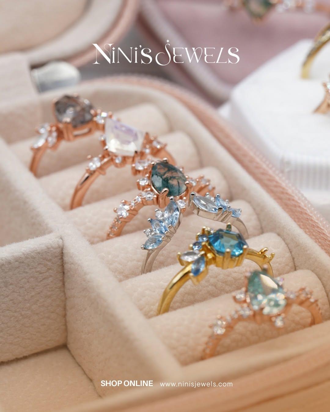 Close-up of rings with gemstones in a jewelry box, with the brand name NiNi's Jewels at the top.