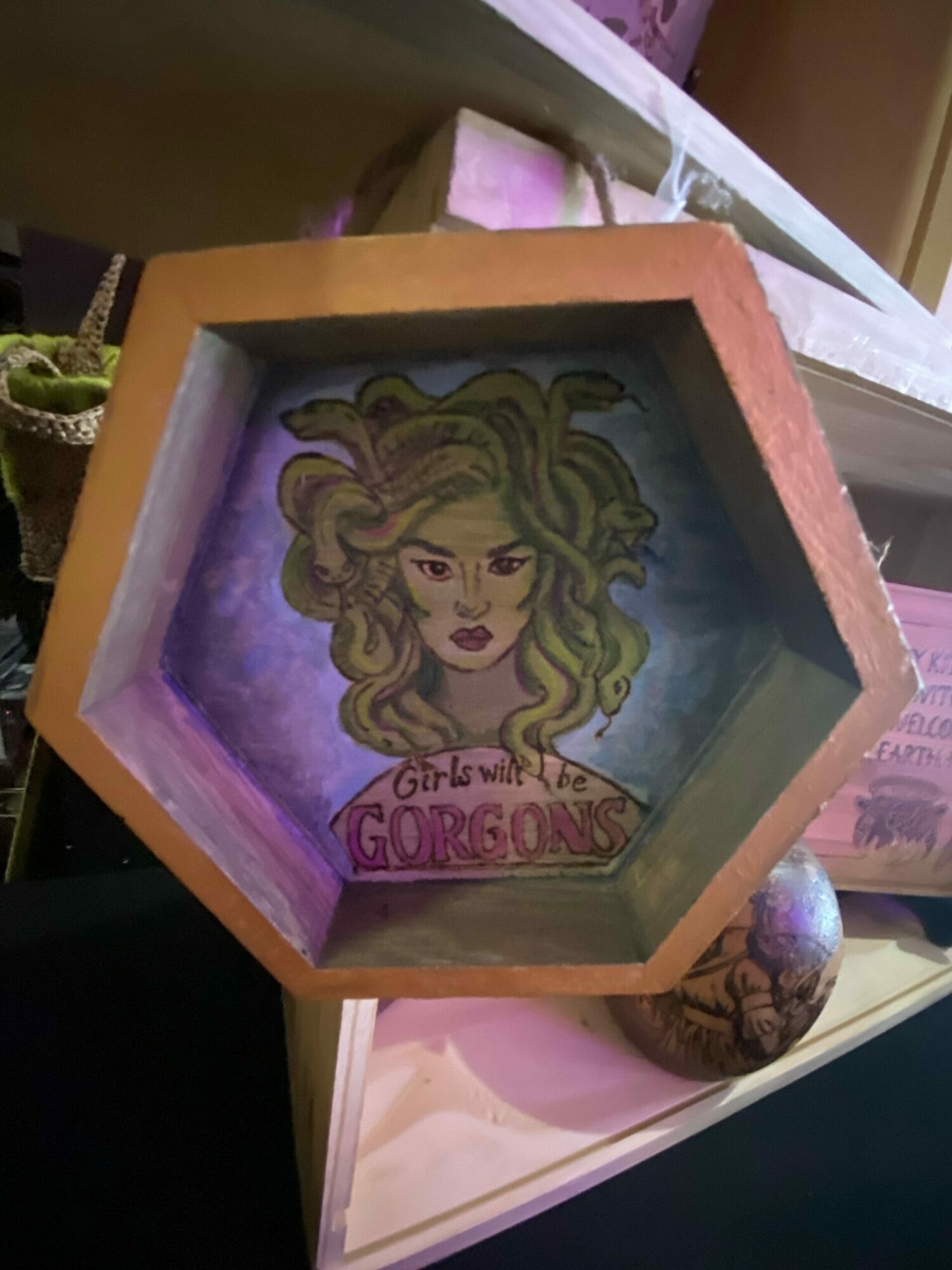 Hexagonal box with a colorful illustration of a woman with curly hair inside, surrounded by pink and purple hues.