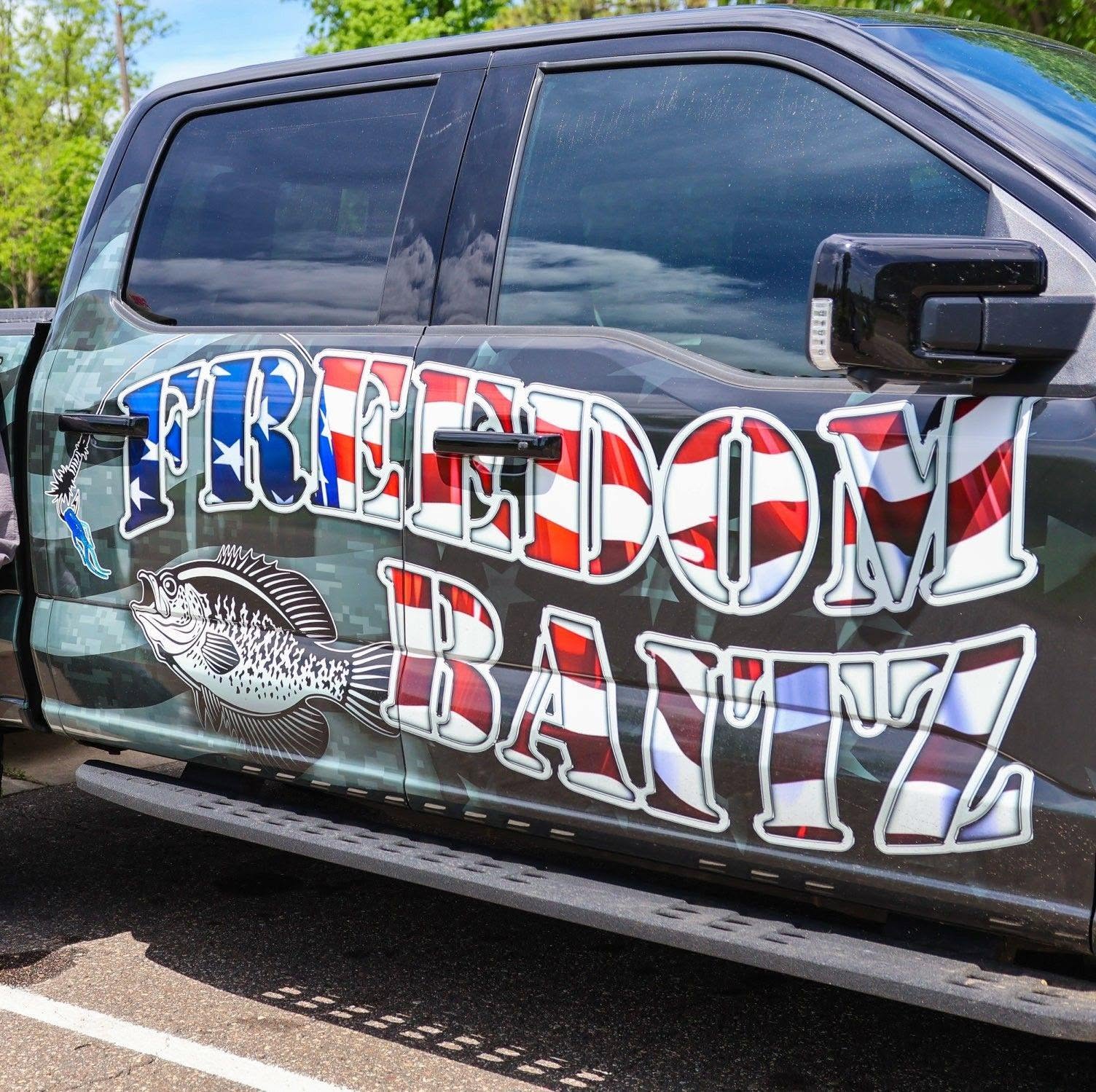 Vehicle with a large graphic text reading 'FREEDOM BANTZ' and a fish illustration, parked outdoors.