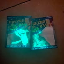 Two books with glowing green and blue covers on a wooden surface, one slightly overlapping the other.