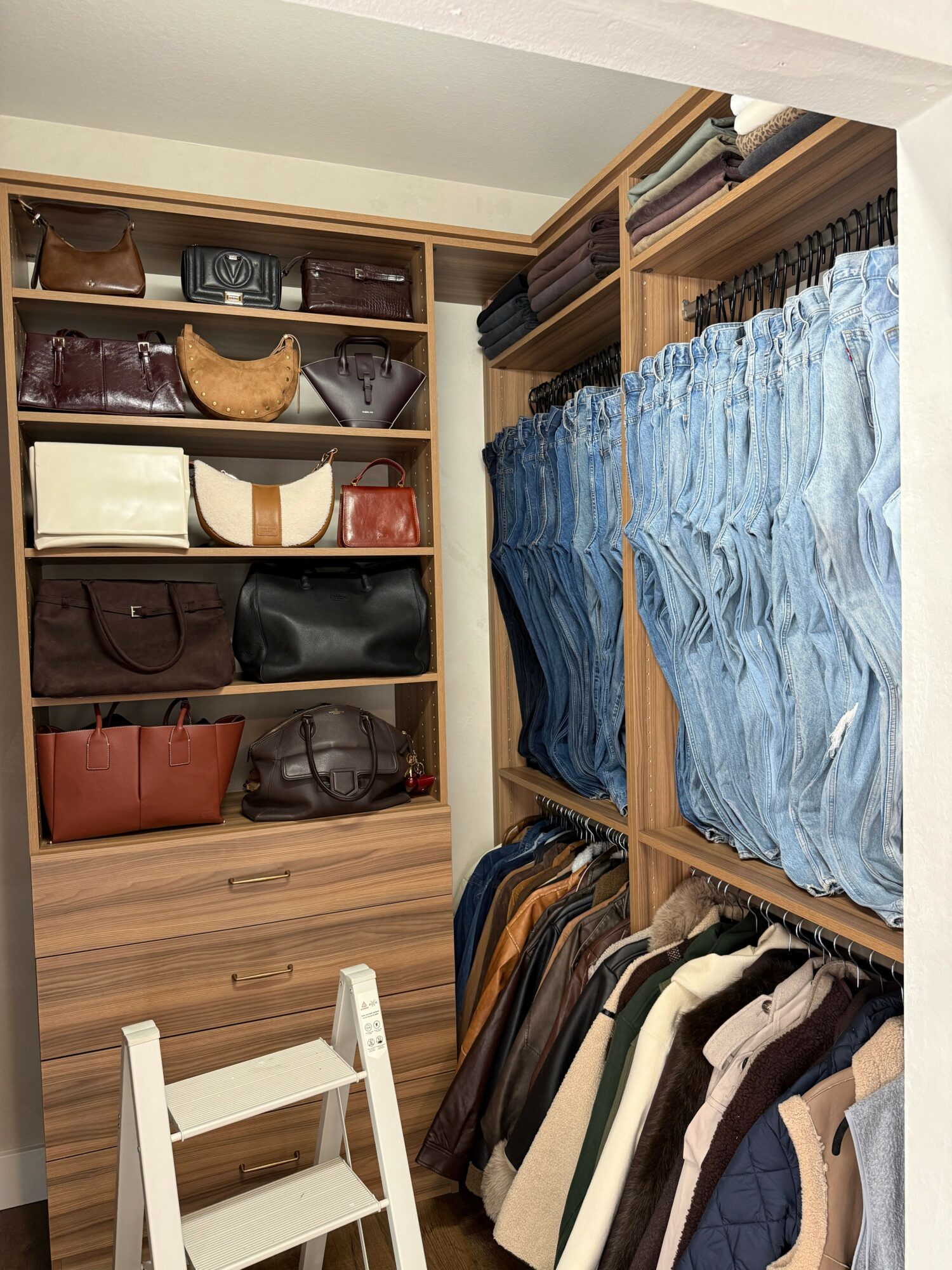 Shelves filled with folded jeans, pants, and bags, viewed from above in a clothing store or closet.