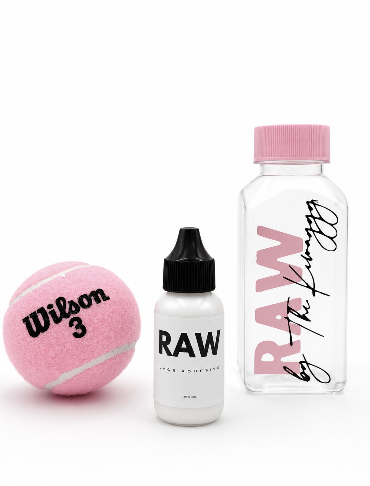 Pink Wilson tennis ball, small RAW bottle with black cap, clear RAW water bottle with pink cap, all on white background.