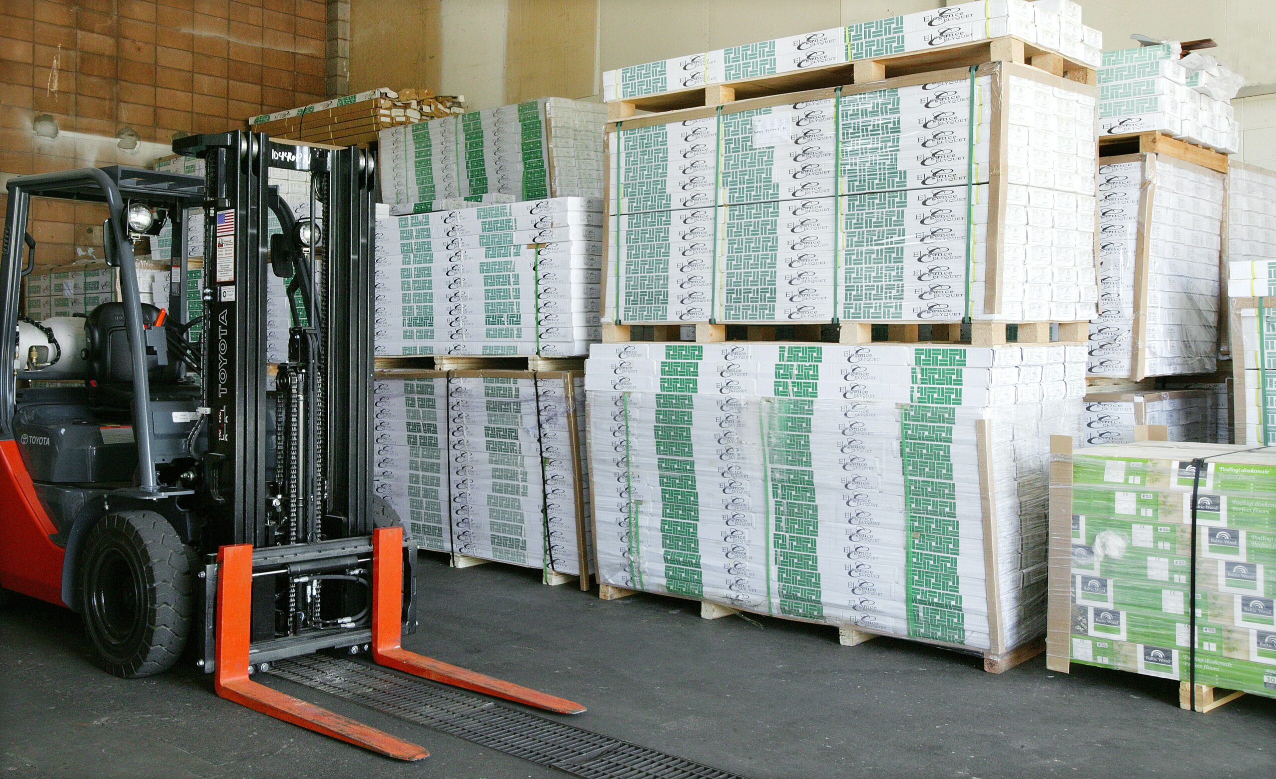 Warehouse with stacked boxes and a forklift in front, organized storage area, concrete floor, wooden wall background.
