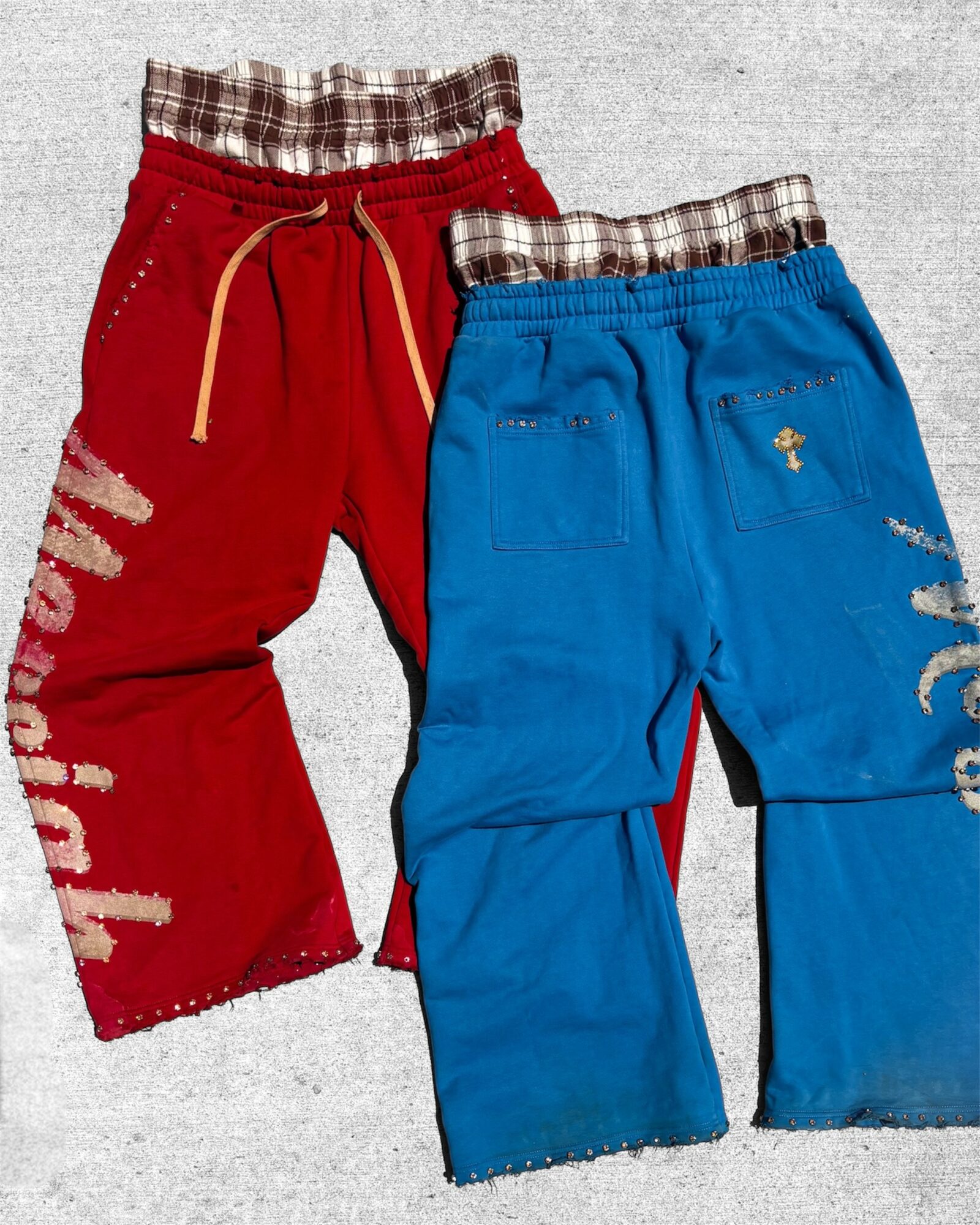 Two pairs of children's pants, one red and one blue, with plaid waistbands and distressed details.