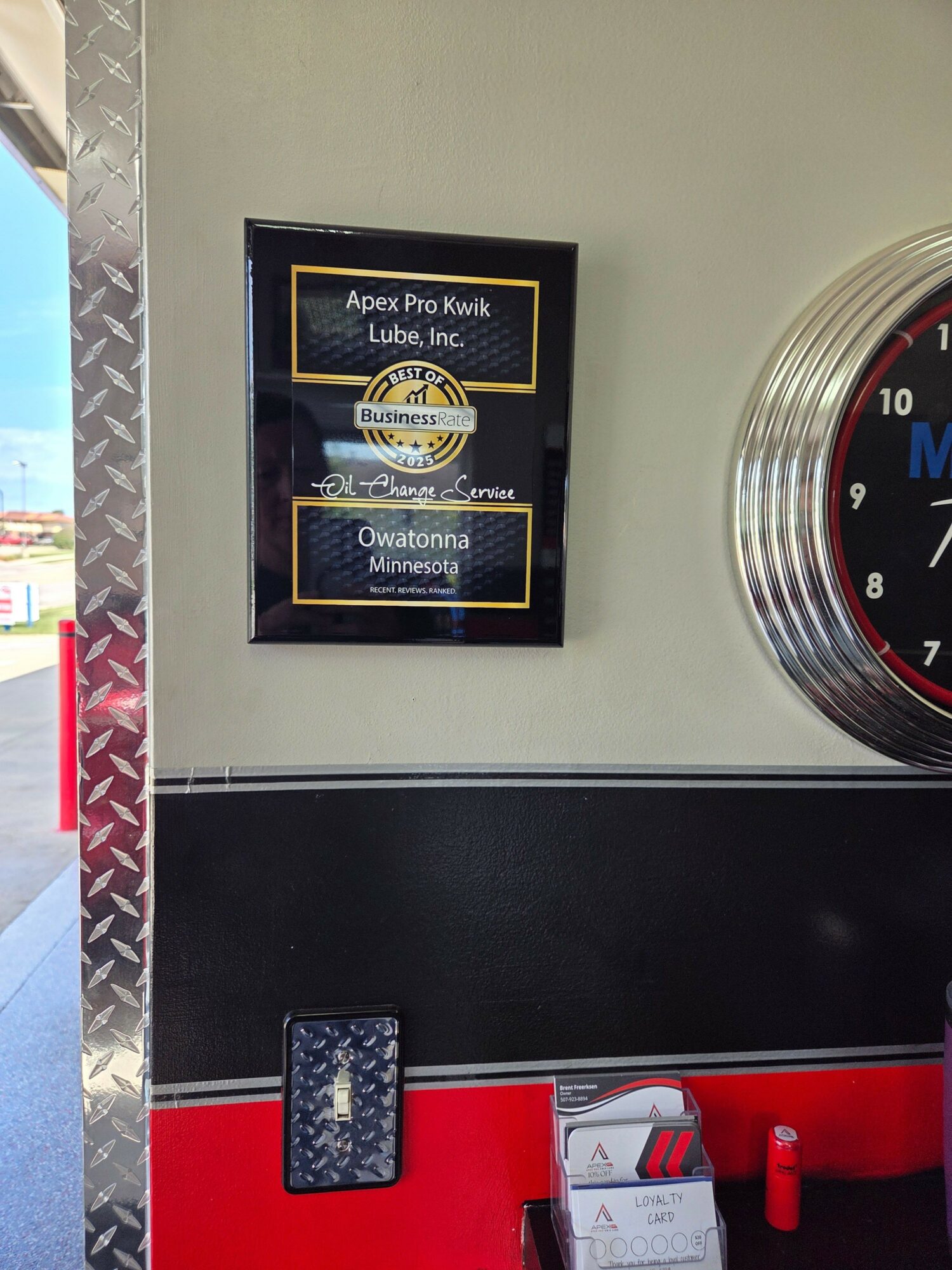 Close-up of a digital screen with options, a clock, and a red and black surface, possibly in a public space.