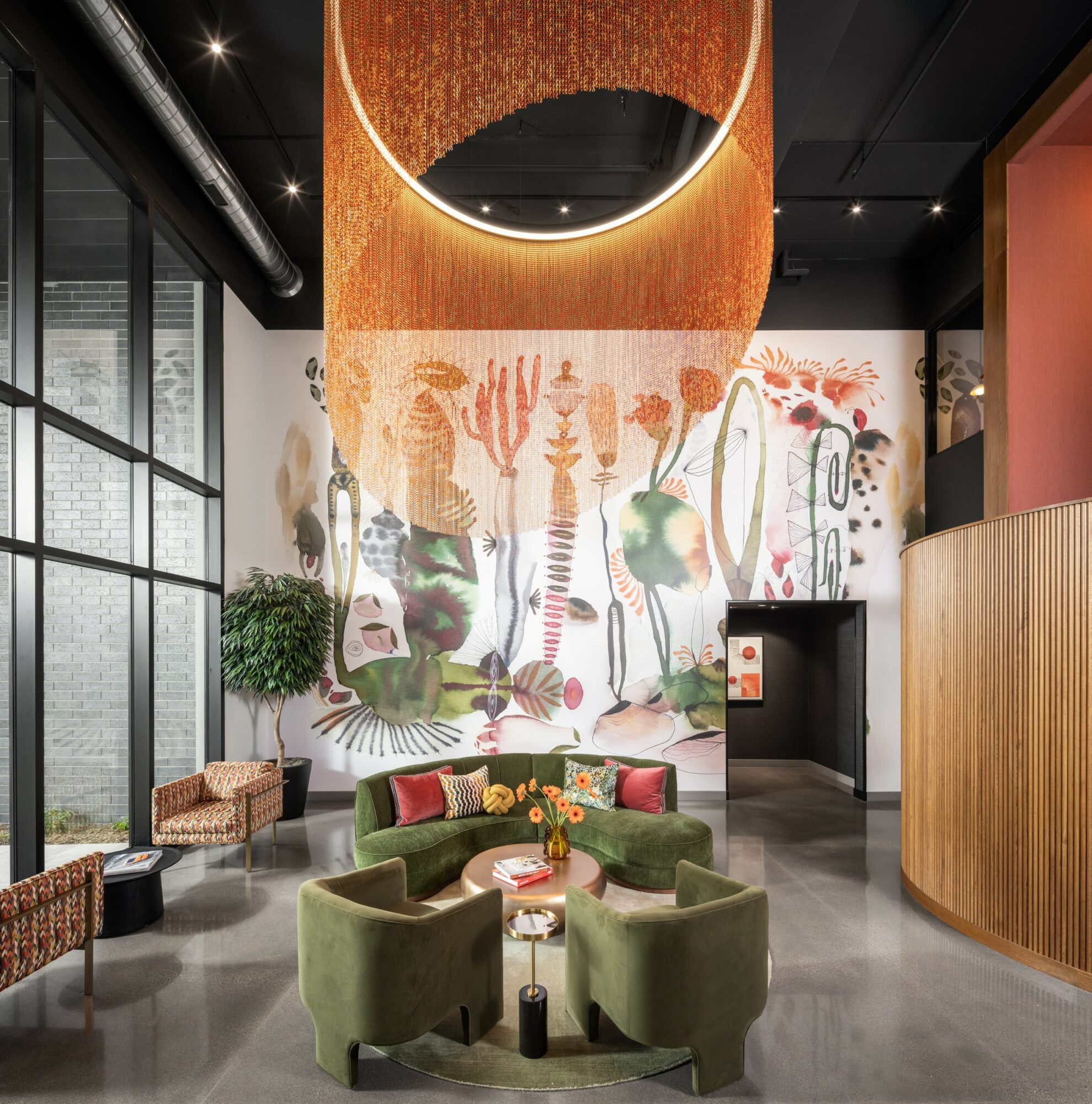Interior space with a circular seating area, large wall mural with plants and abstract art, and a round mirror above. Word count: 20