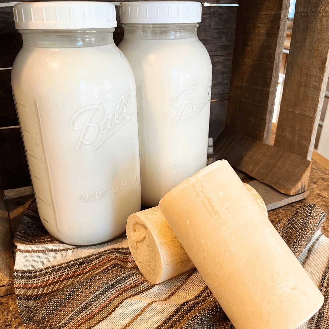 Two bottles of milk and two rolled cheese slices on a striped cloth, with wooden background.