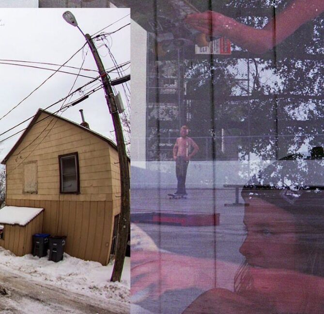 A person standing outside near a house with snow, seen through a glass window with reflections of trees and a person inside.