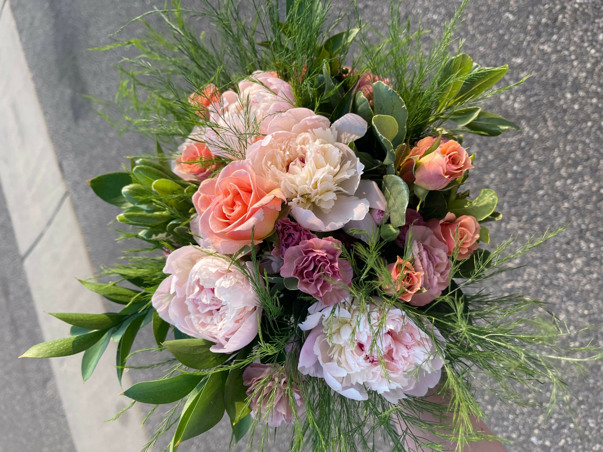 A bouquet of pink, white, and purple flowers with green foliage on a gray surface.