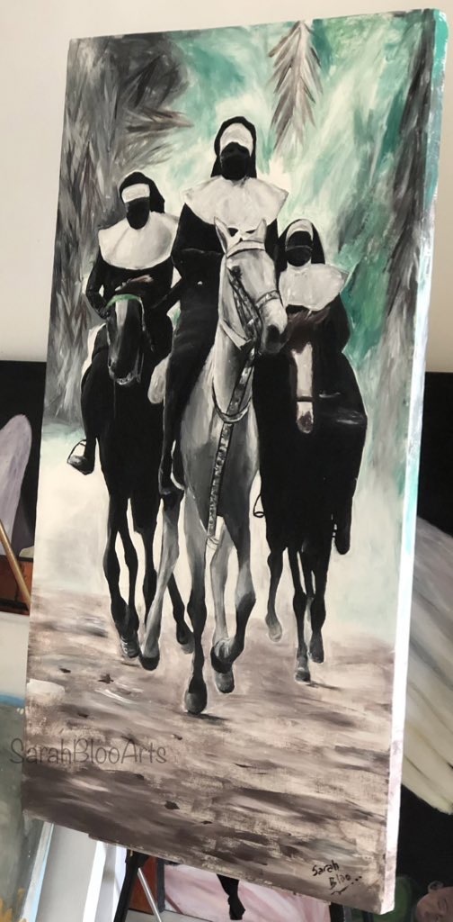 Four people riding horses through a forest, wearing helmets and masks, with trees in the background.