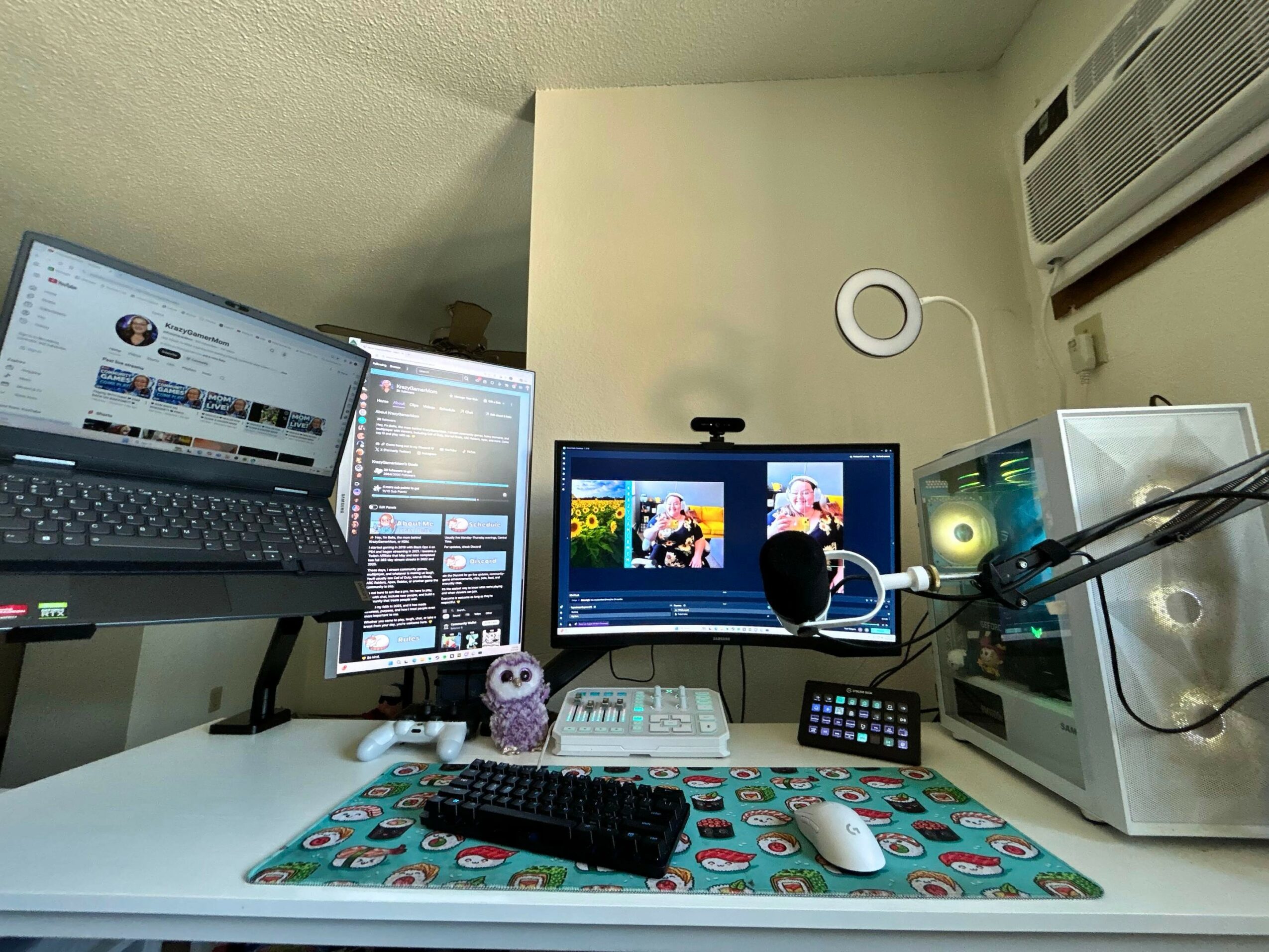 Computer desk with multiple monitors, keyboard, mouse, and audio equipment in a room corner.