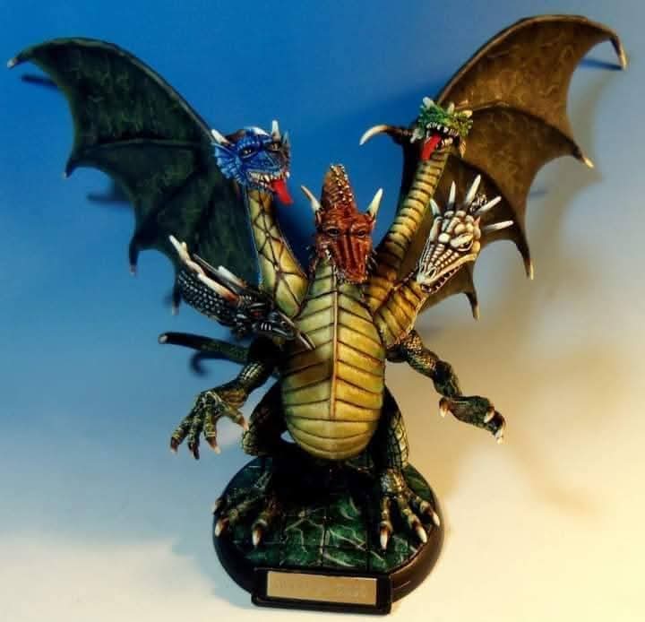 A multi-headed dragon sculpture with colorful, detailed heads and large wings, standing on a base with a plaque.