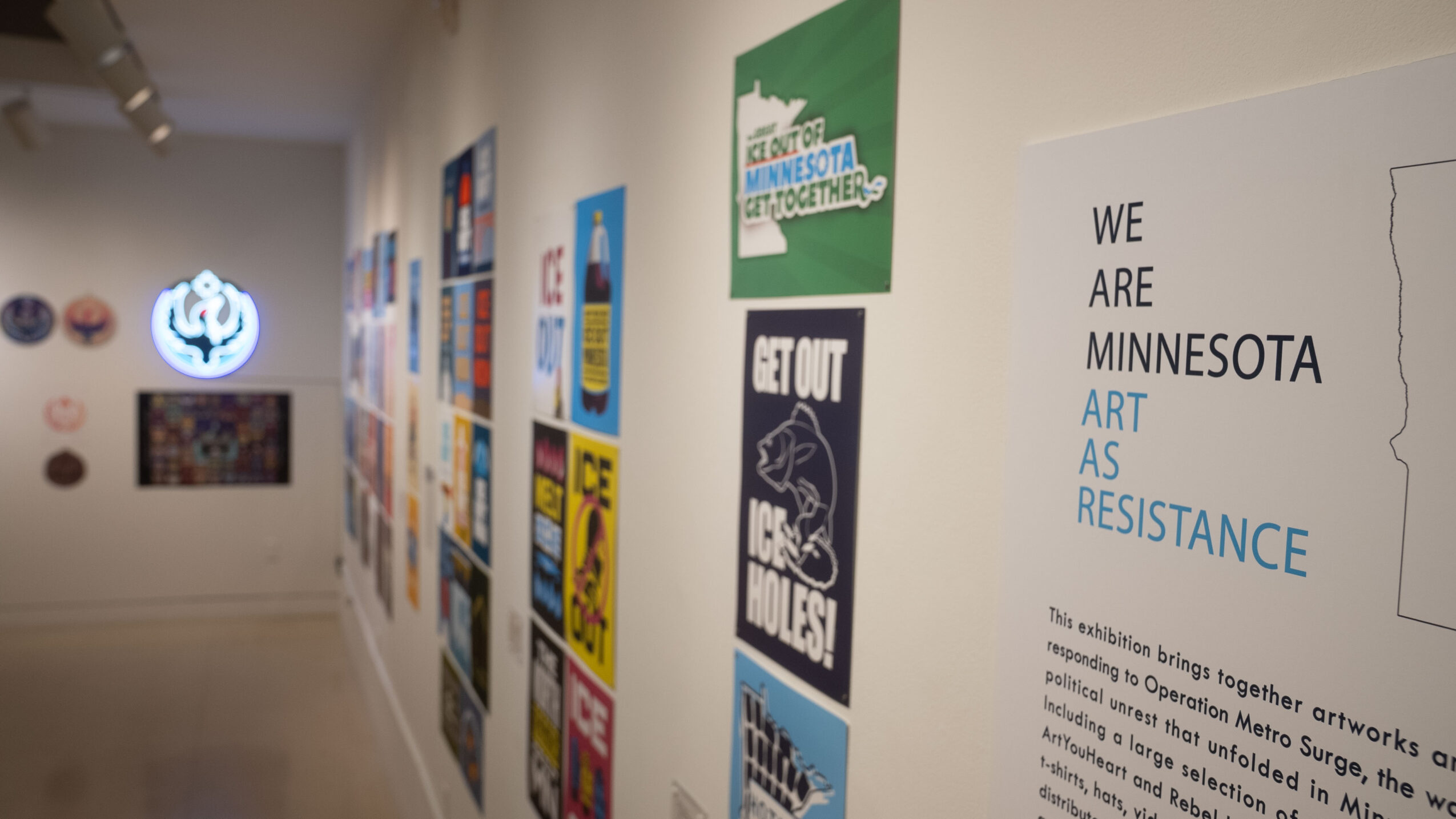 Gallery wall with various colorful posters and artwork displayed, with a white wall and ceiling in the background.