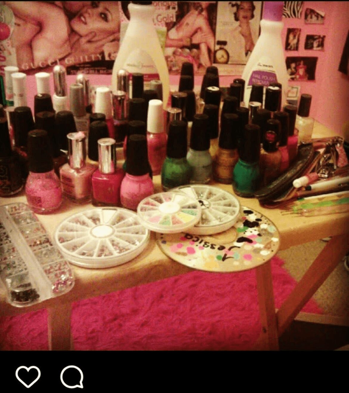 Nail polish bottles and nail art supplies on a cluttered table with photos and posters in the background.