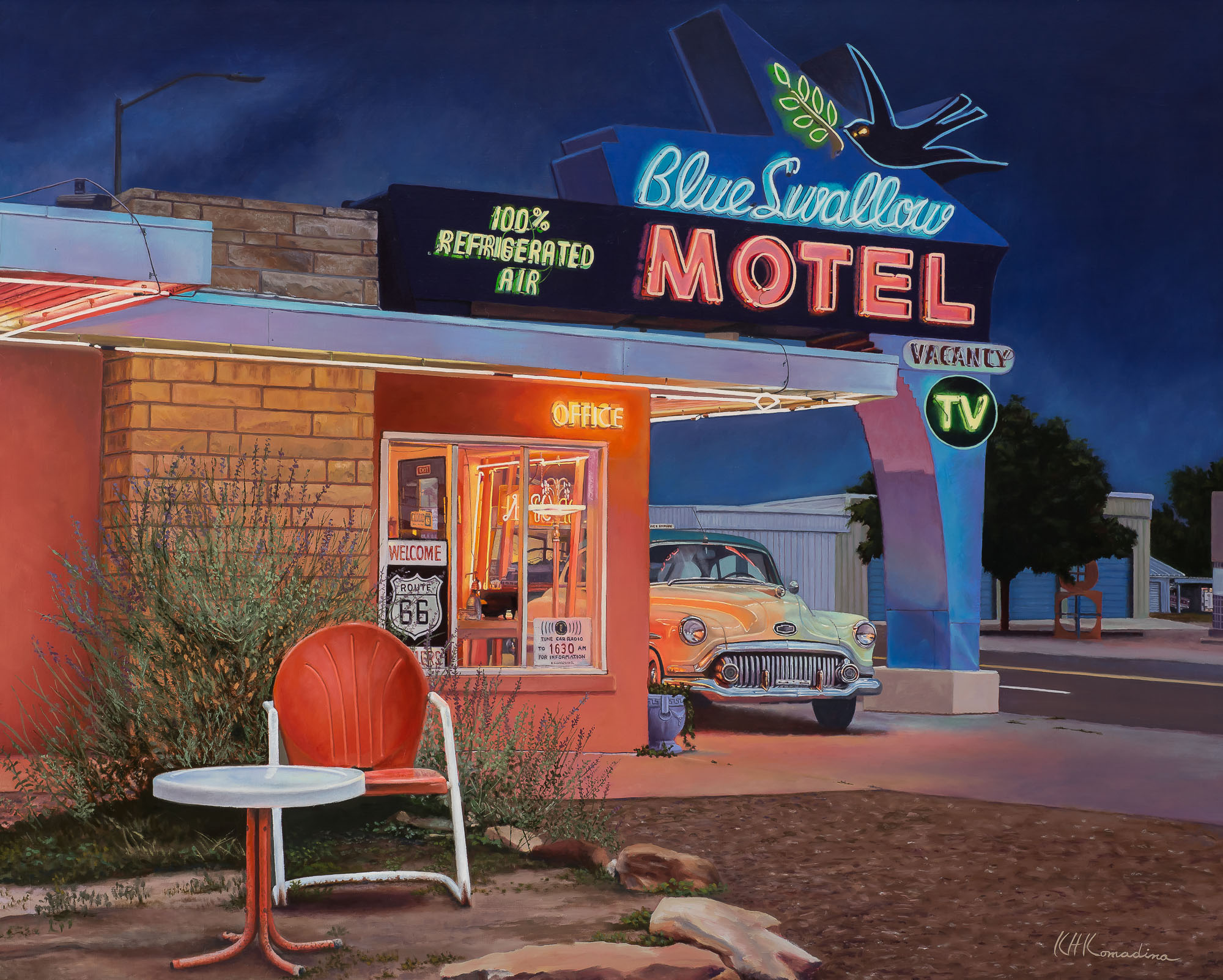 Night scene of a motel with neon signs, a vintage car, and a red chair outside the office.