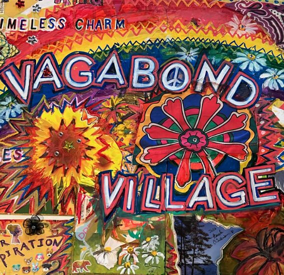 Colorful carnival sign with the words 'VAGABOND VILLAGE' surrounded by bright decorations and patterns.
