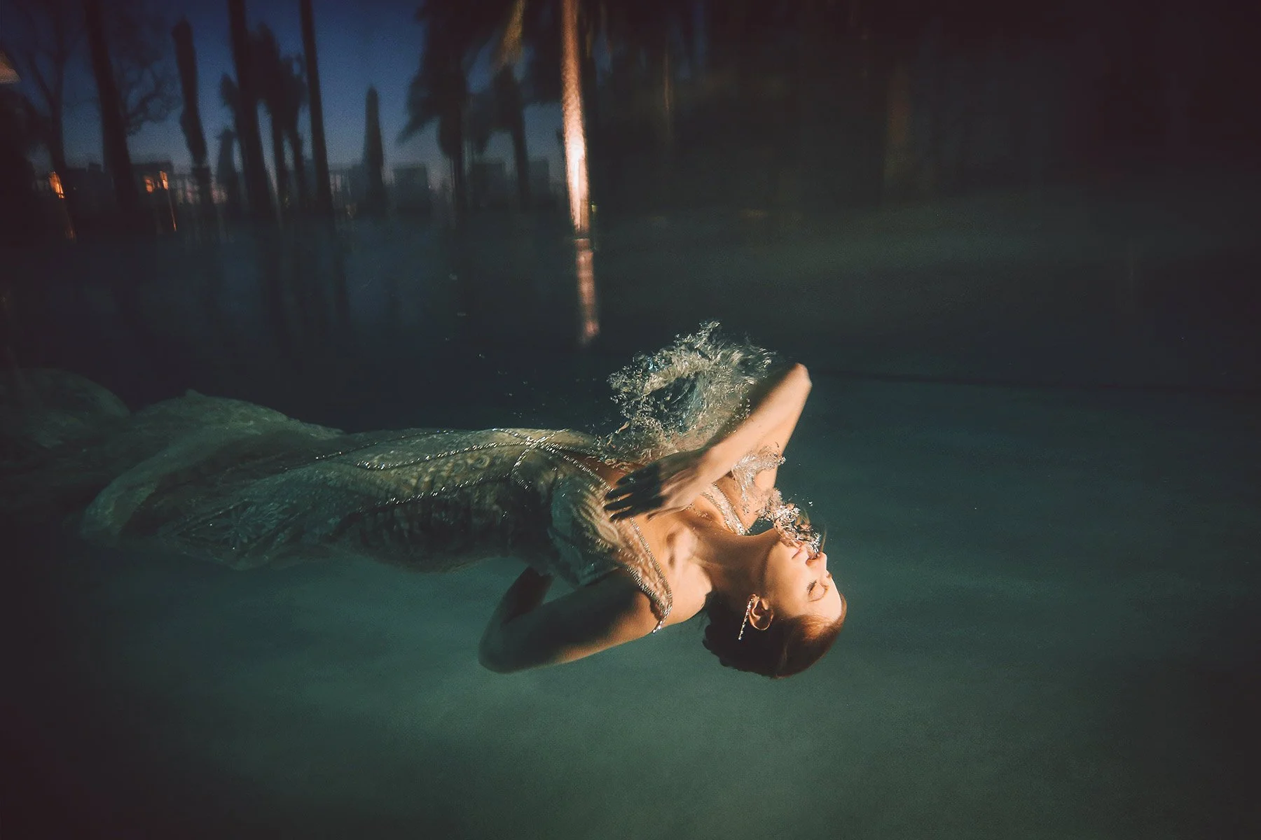 Person floating in water at night, with trees and reflections in the background.