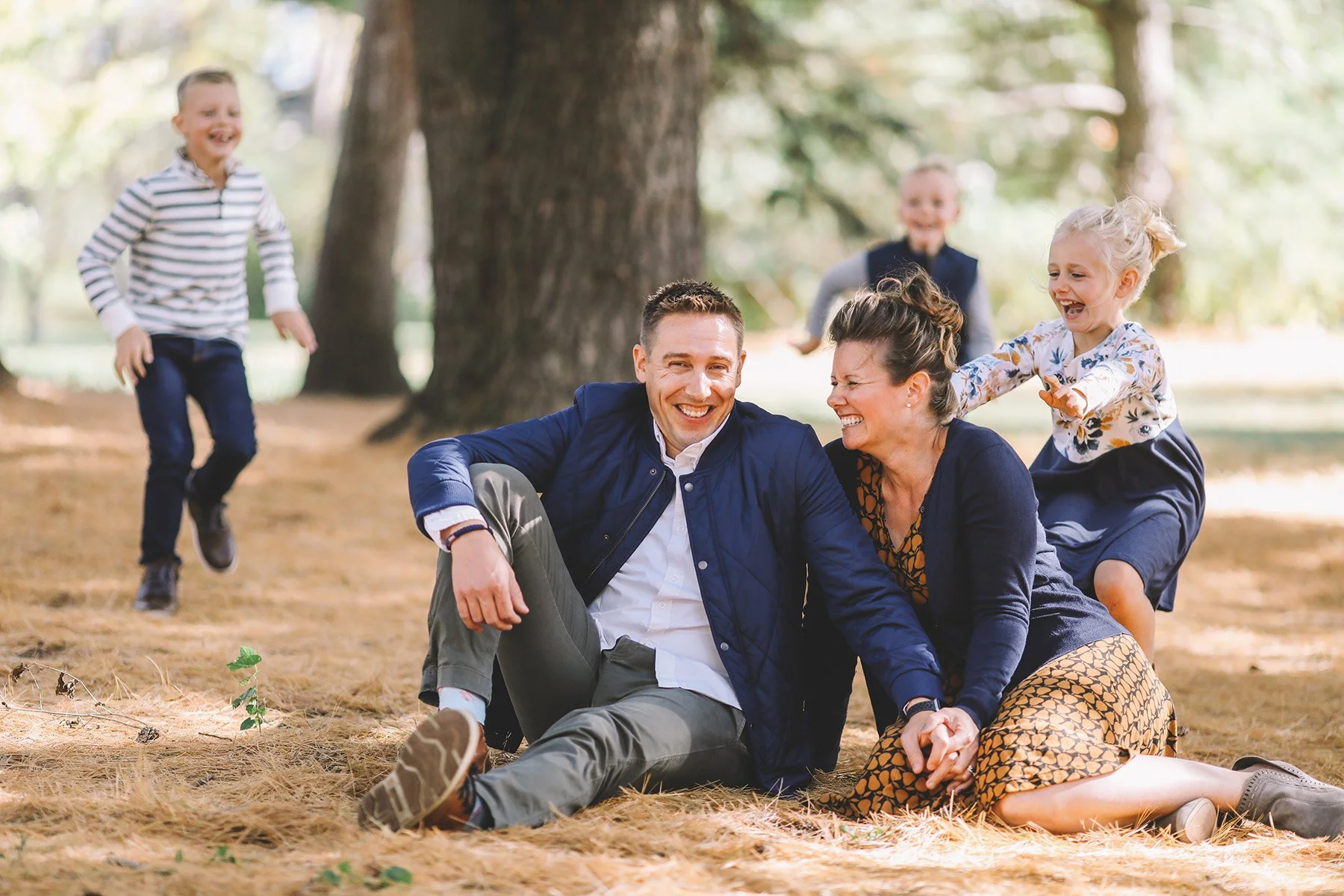 Group of people sitting and playing outdoors in a park, smiling and enjoying each other's company.