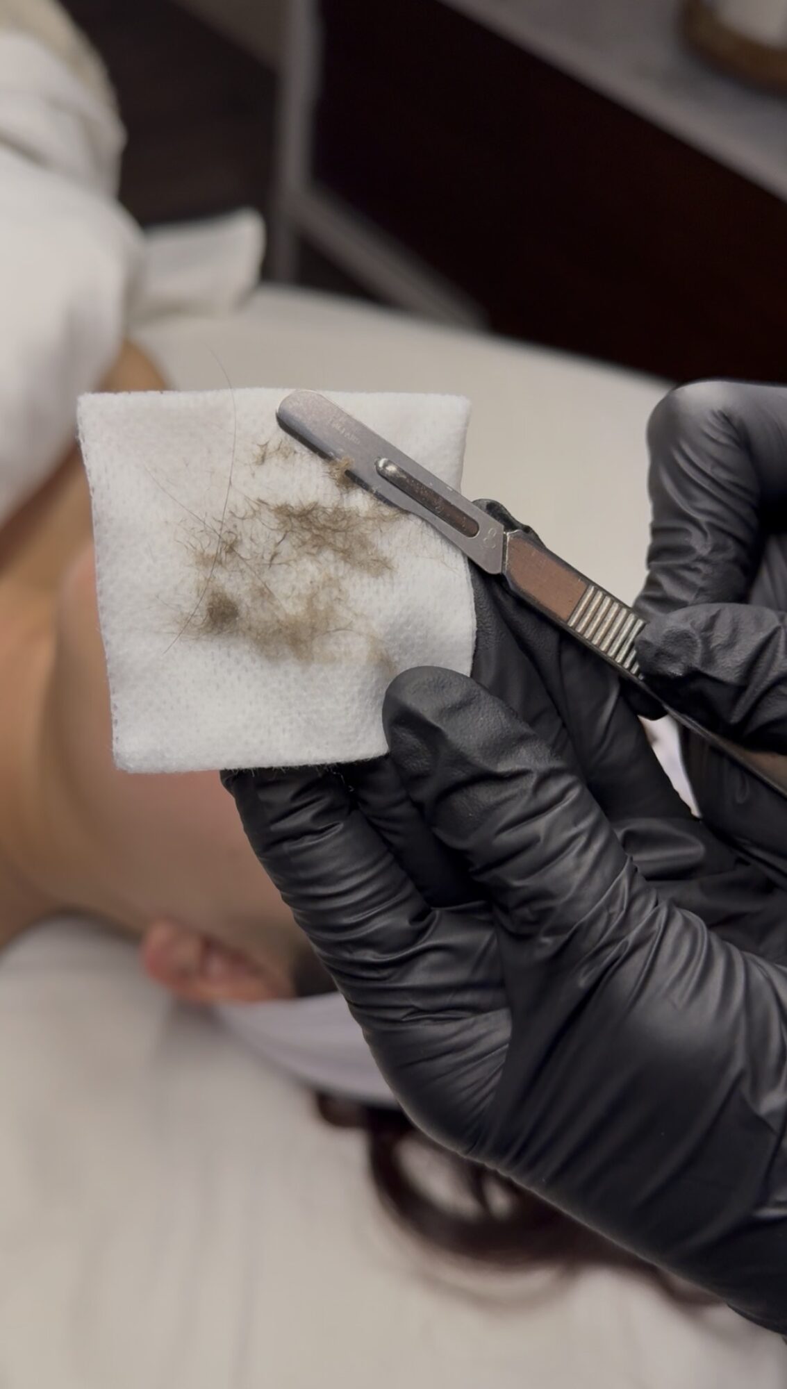 Person wearing black gloves holding a small tool and a white cloth with dirt, in a close-up view.