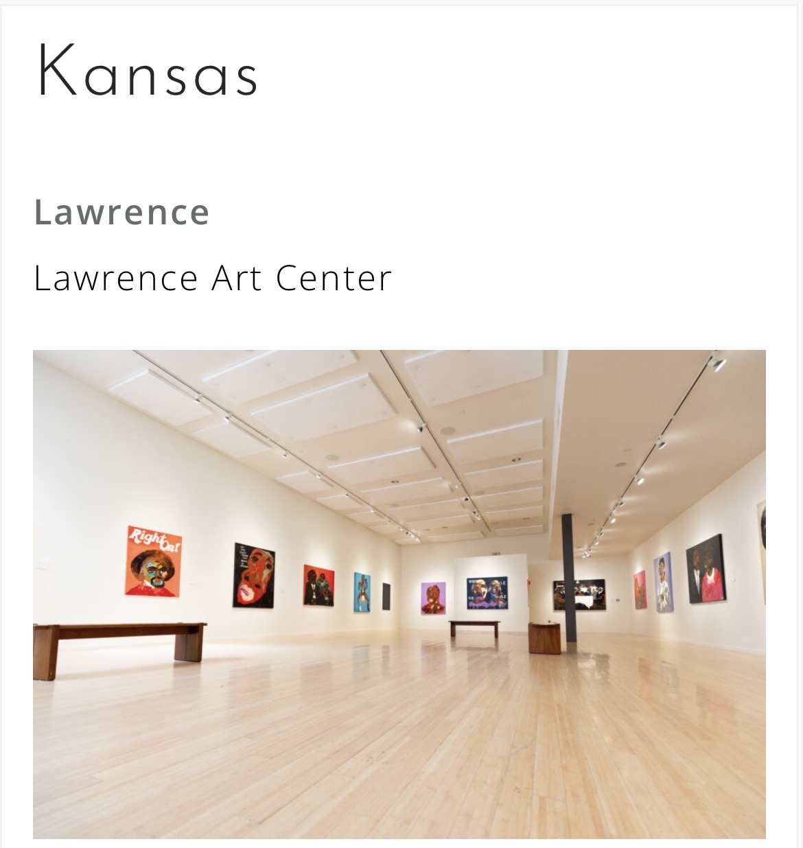Gallery with colorful paintings on white walls and wooden floors, benches, and ceiling lights, at Lawrence Art Center in Kansas.
