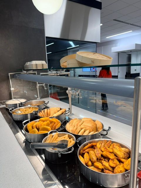 Display of various baked goods including pies and pastries behind a glass counter, with a modern kitchen background.