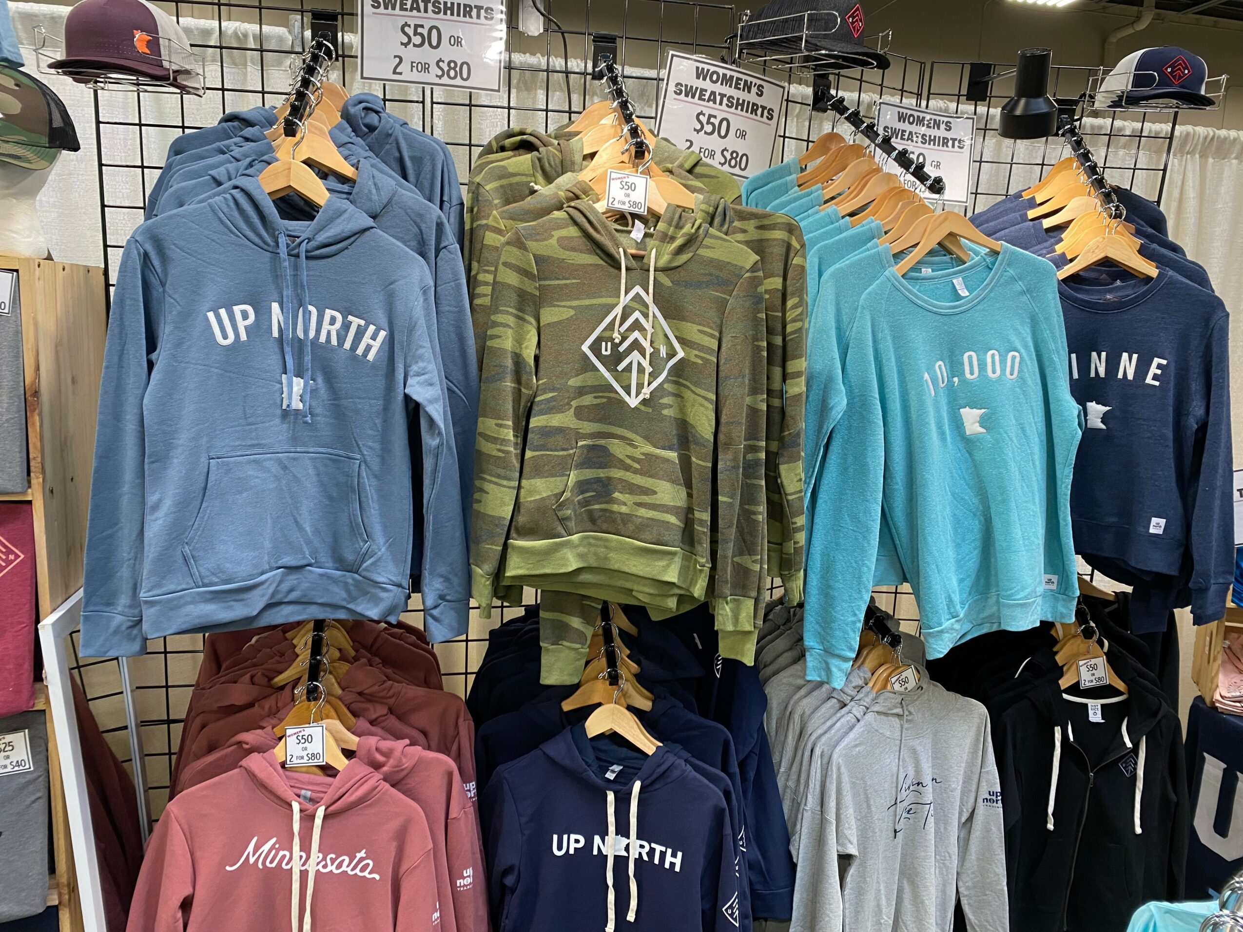 Display of hoodies and sweatshirts in various colors and patterns hanging on a grid wall.