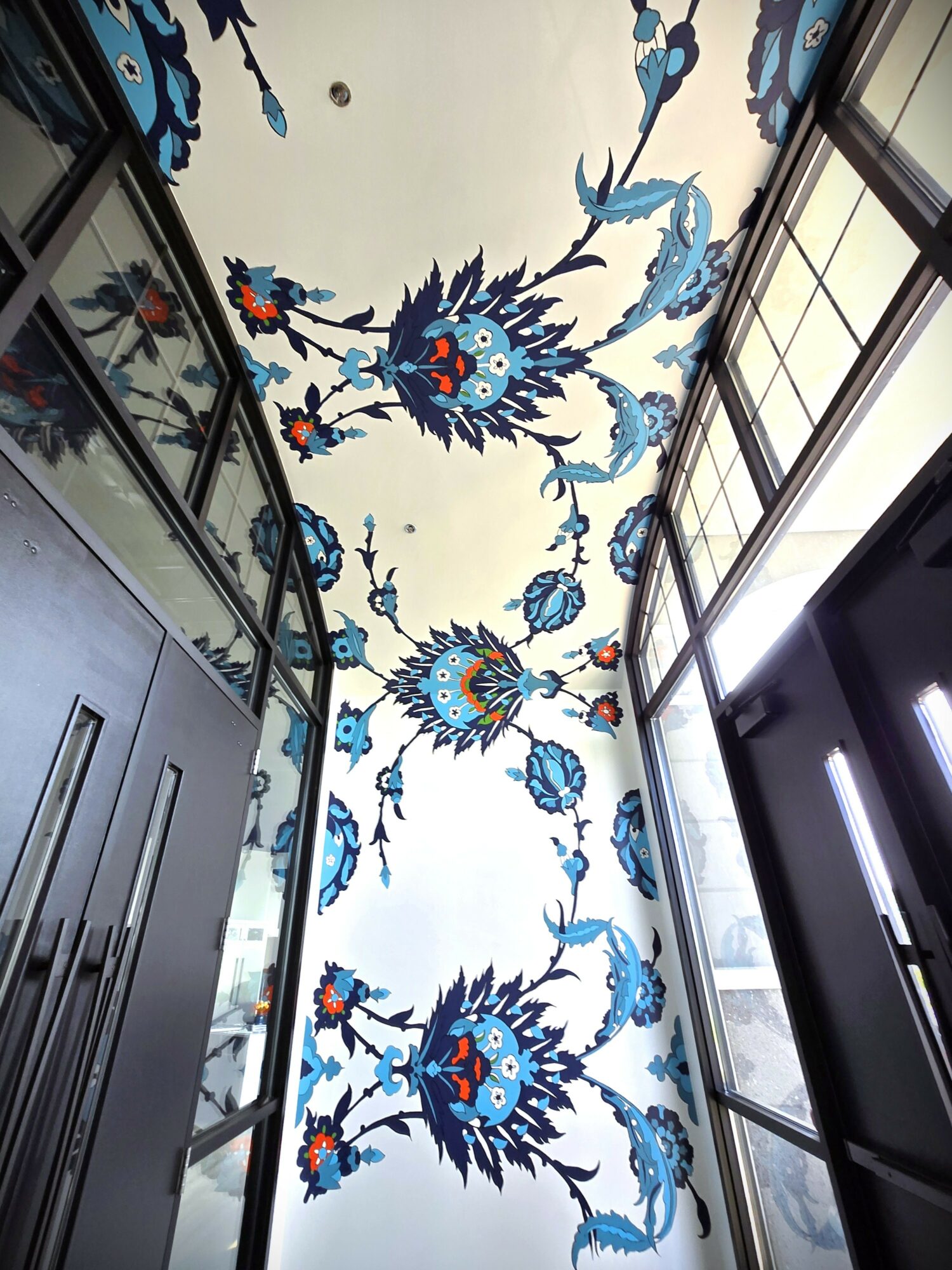 Ceiling with blue floral pattern, viewed from below, with glass windows on sides.