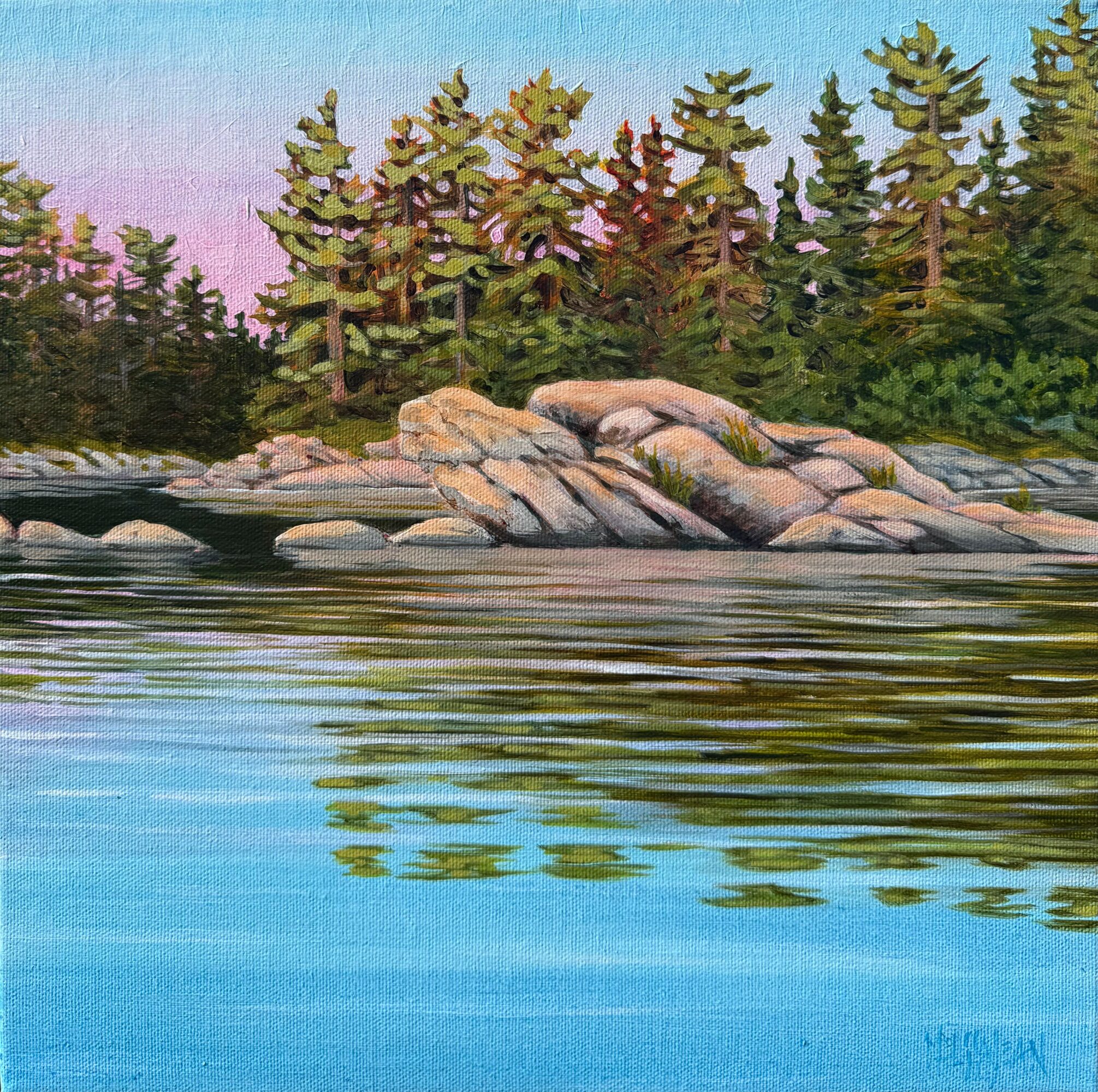 Calm lake with rocks and pine trees in the background, reflected in the water, under a pink and blue sky.