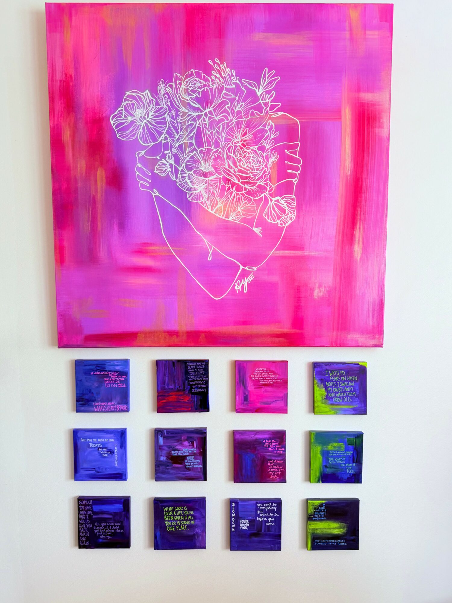Pink abstract painting with a white line drawing of a person's face and hair, displayed on a white wall.
