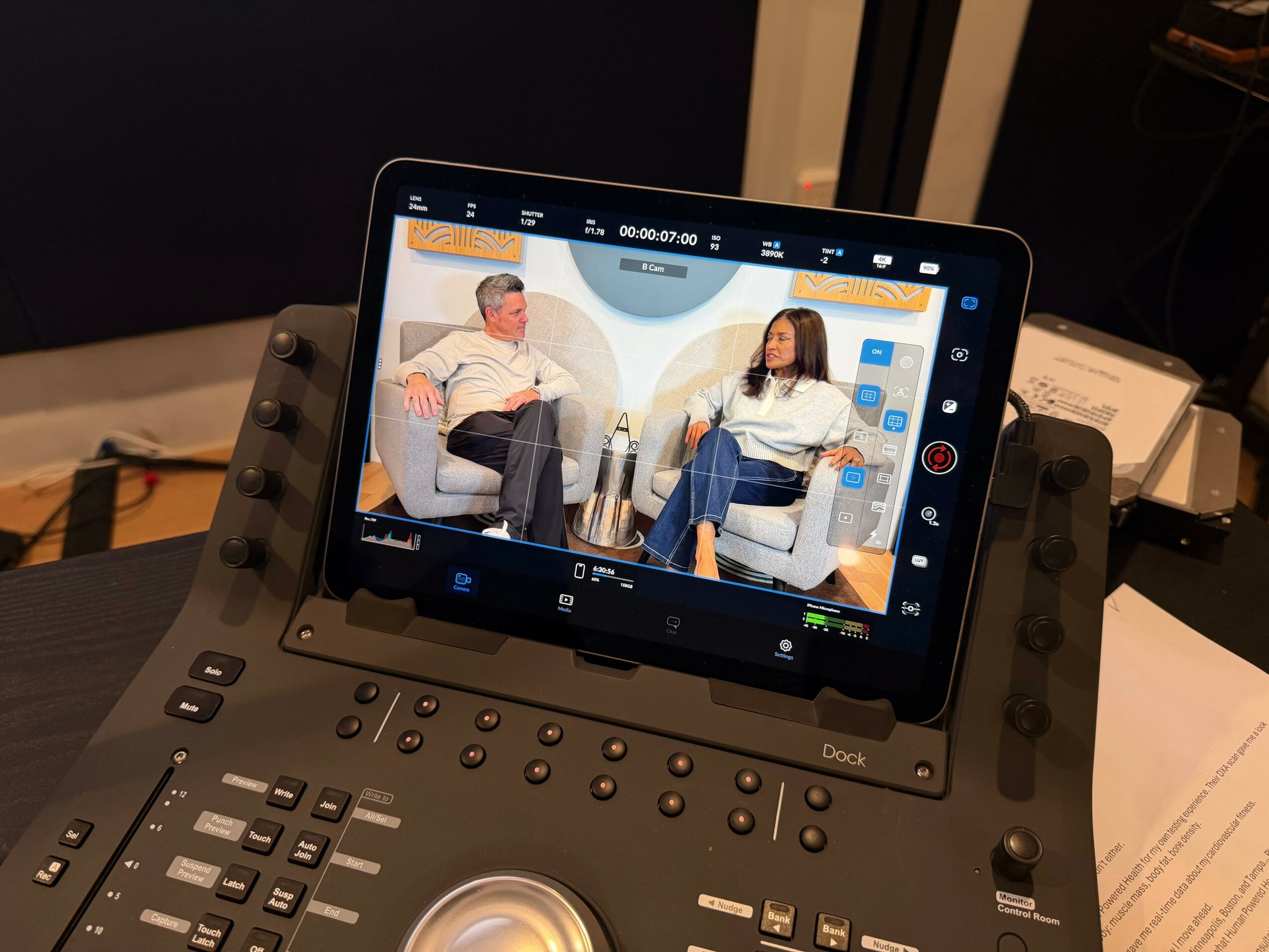 Tablet mounted on a stand displaying two people talking in a studio setting.