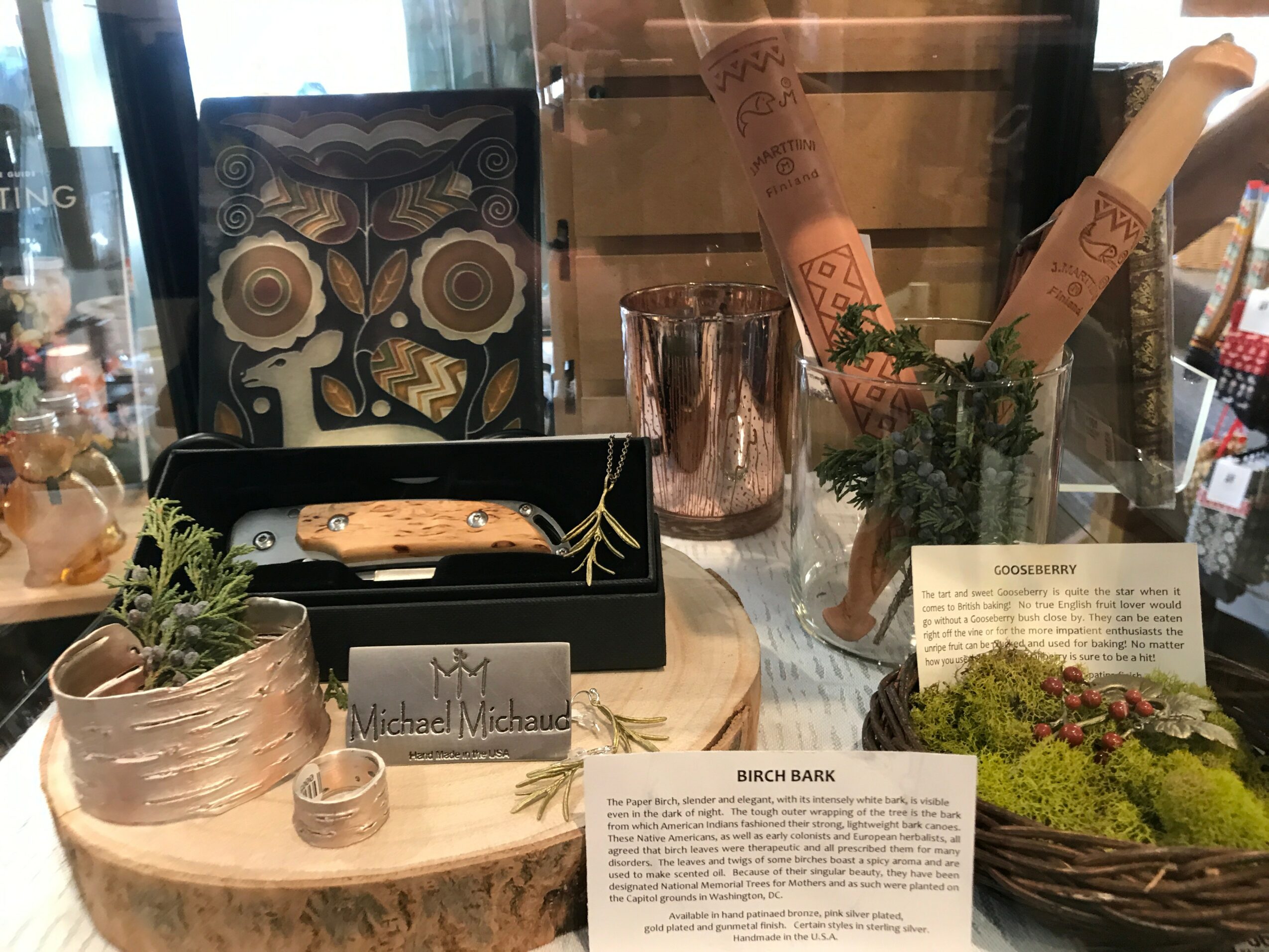 Display table with decorative items, plants, and informational cards in a store setting.