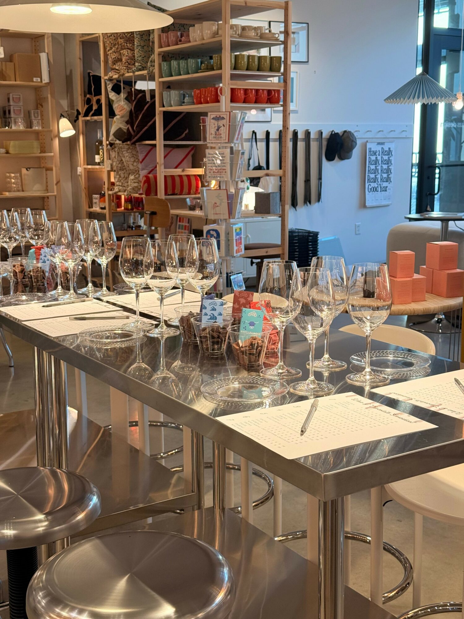 A kitchen counter with various bottles, glasses, and utensils, with shelves and kitchen items in the background.